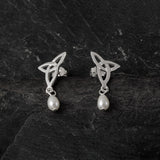A pair of silver trinity knot shaped stud earrings with dangling white teardrop pearls