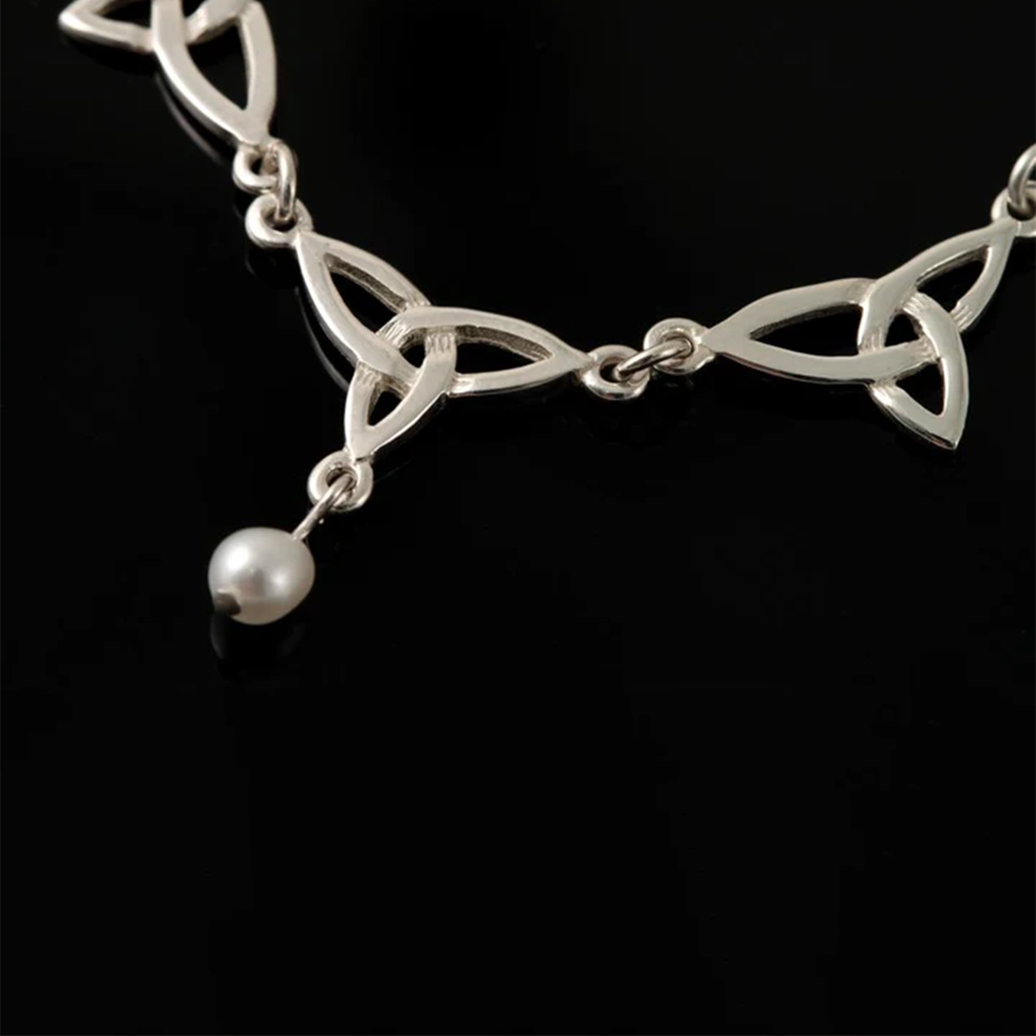 A triple link trinity knot silver necklace with a single dangling white teardrop pearl