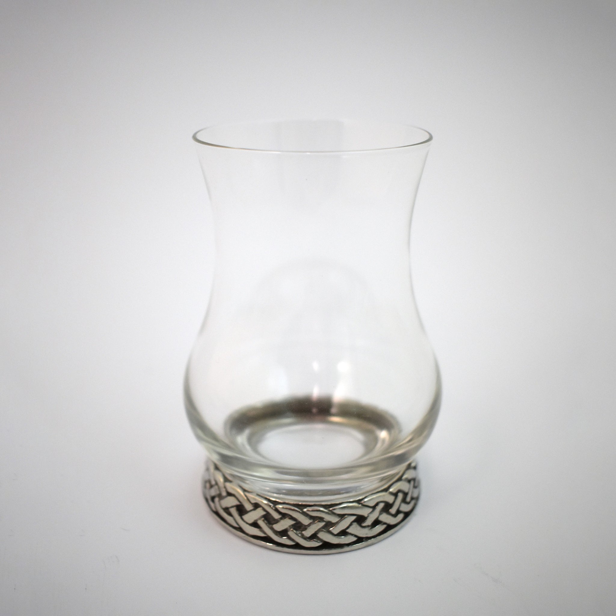 A whisky glass with pewter base engraved with a celtic knot