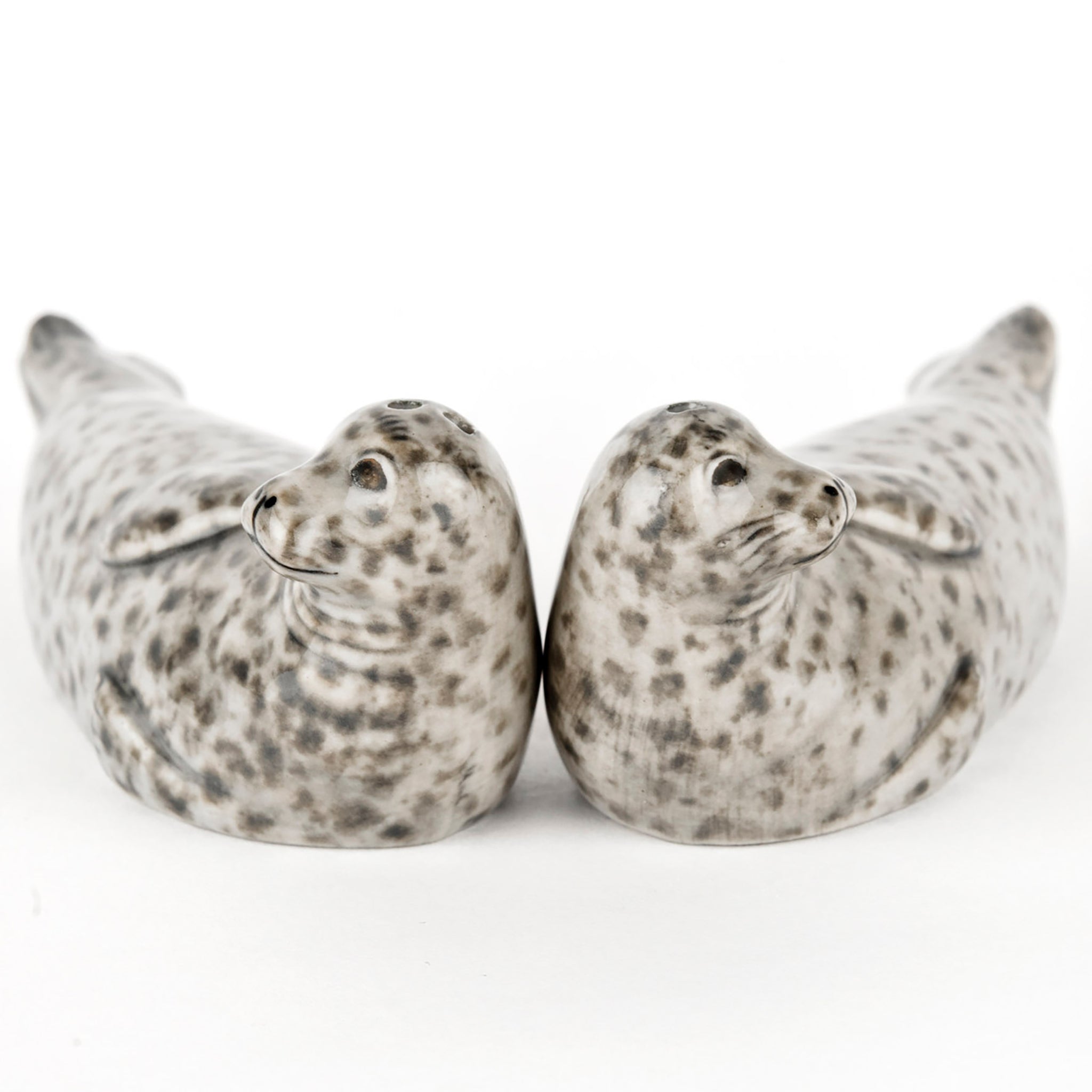 Front view of a pair of glazed ceramic salt and pepper shakers in the shape of grey spotted seals