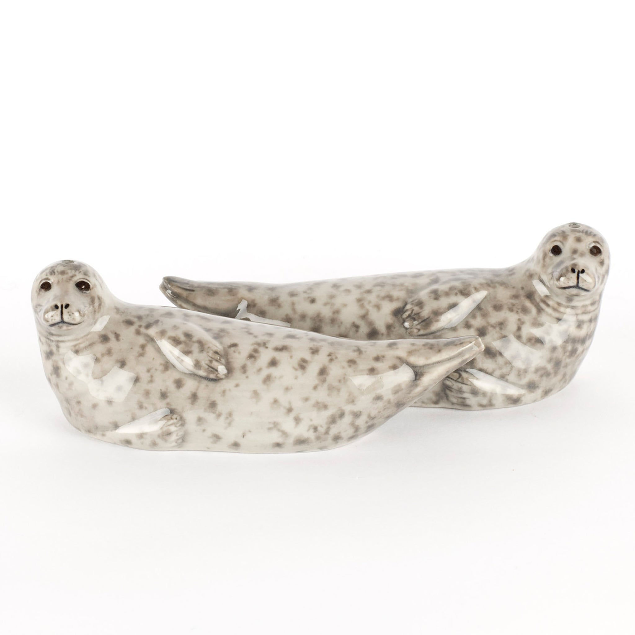 A pair of glazed ceramic salt and pepper shakers in the shape of grey spotted seals