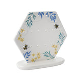 A ceramic hexagon shaped earring holder with bee design 