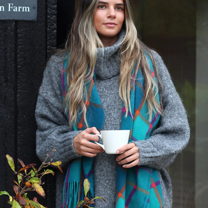 Model wearing teal, purple and orange check scarf with tassel fringe