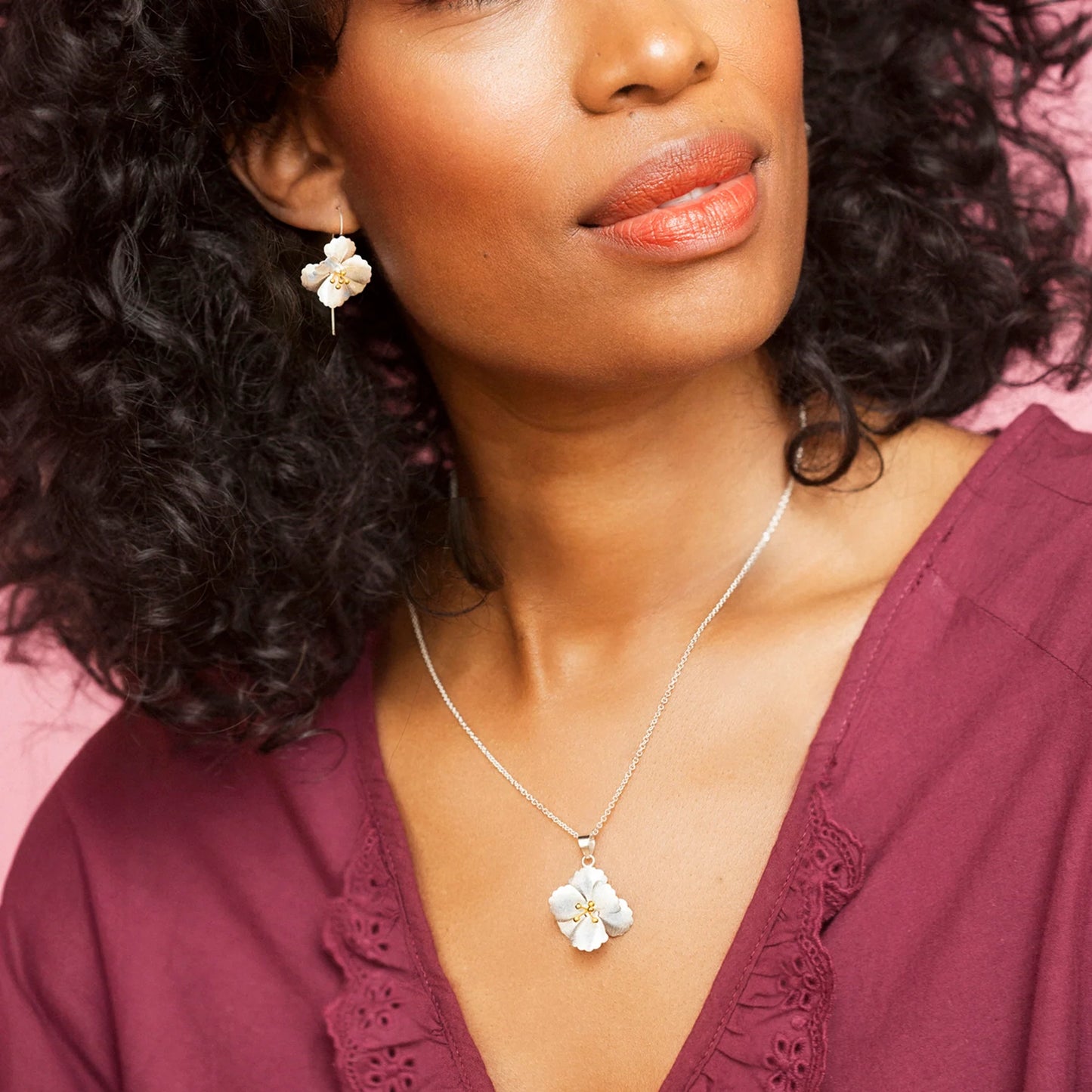 Model wearing satin silver cherry blossom shaped pendant with gold stamen details and silver chain