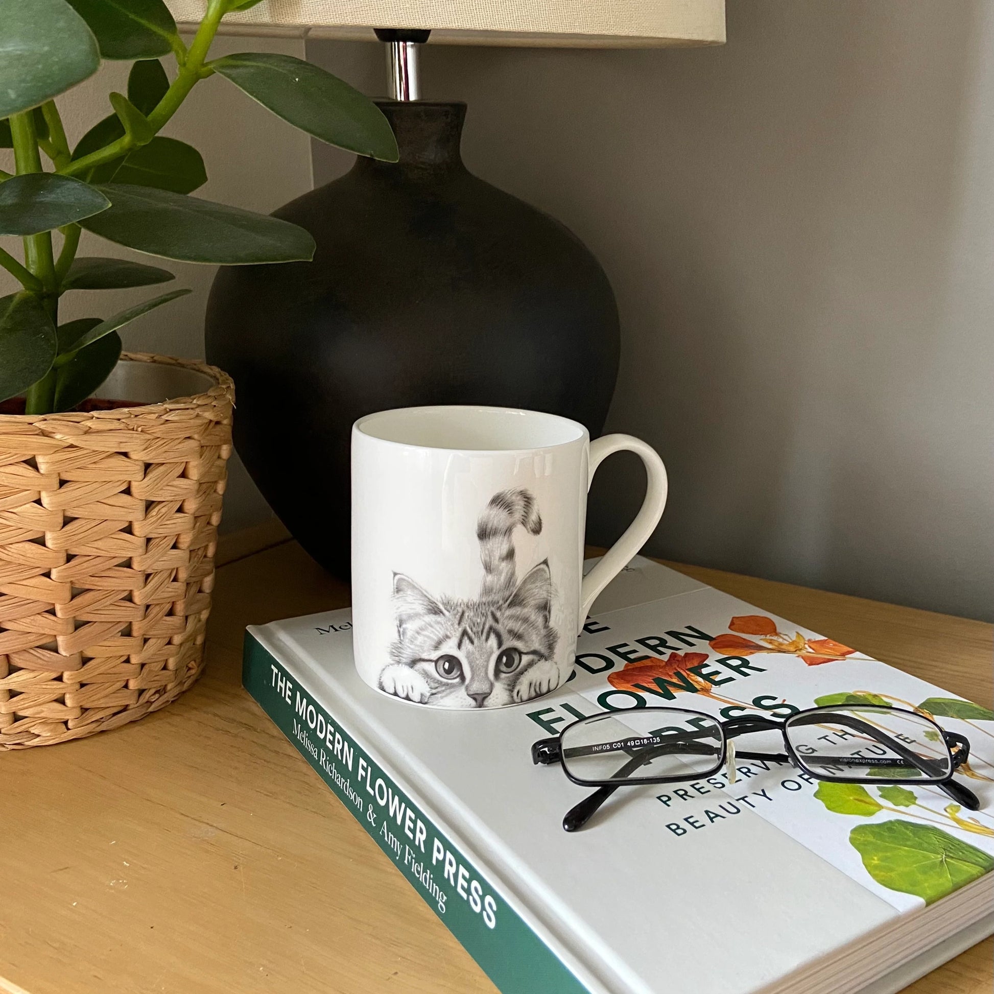 White mug featuring a grey peeking cat illustration - lifestyle