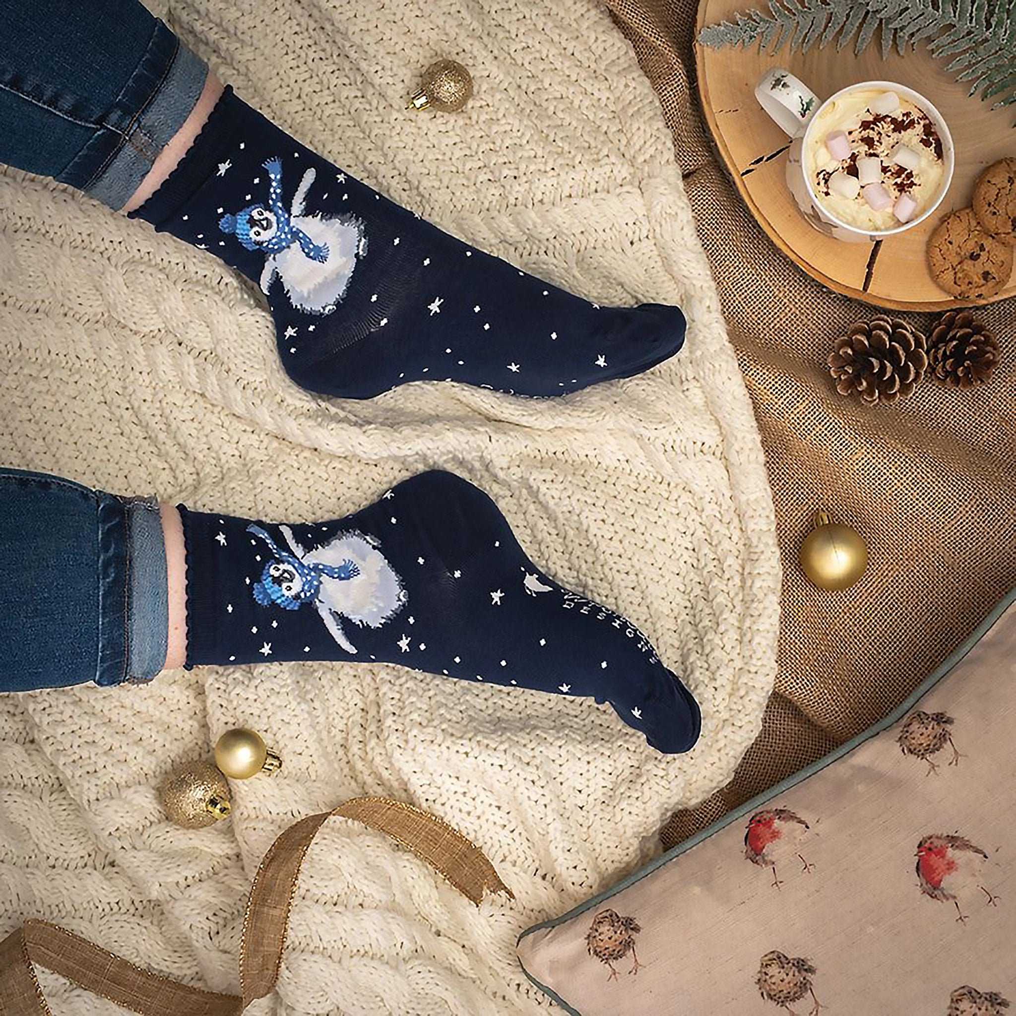 Model wearing pair of Christmas socks in navy with a penguin in hat and scarf lifestyle