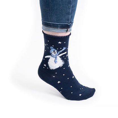 Model wearing pair of Christmas socks in navy with a penguin in hat and scarf