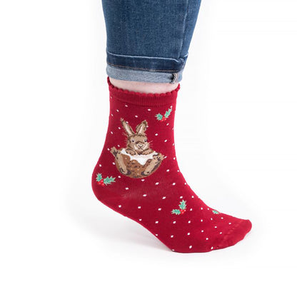 Model wearing pair of Christmas socks in red with a rabbit in a Christmas pudding 