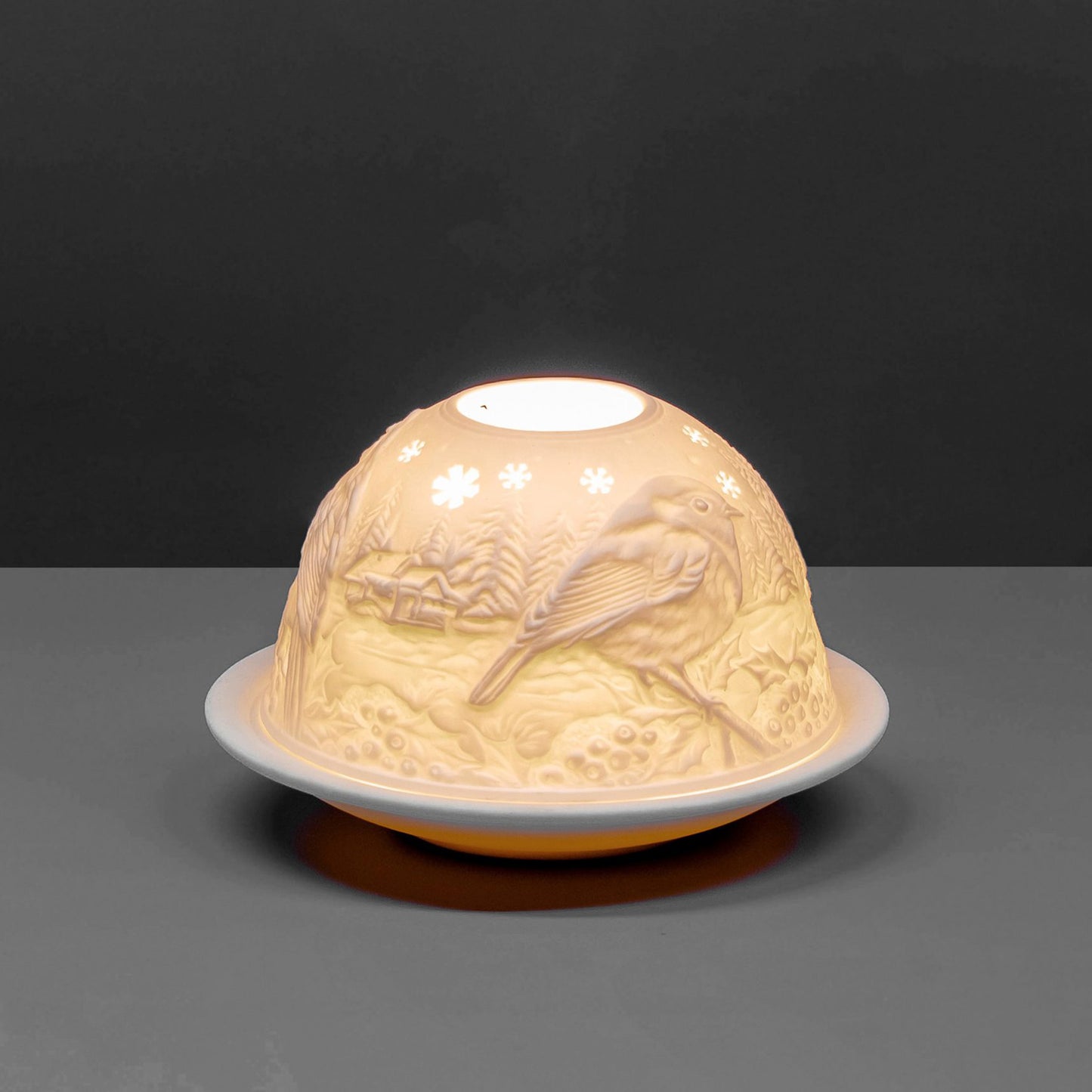 White porcelain dome candle holder with a Christmas robin design lit up