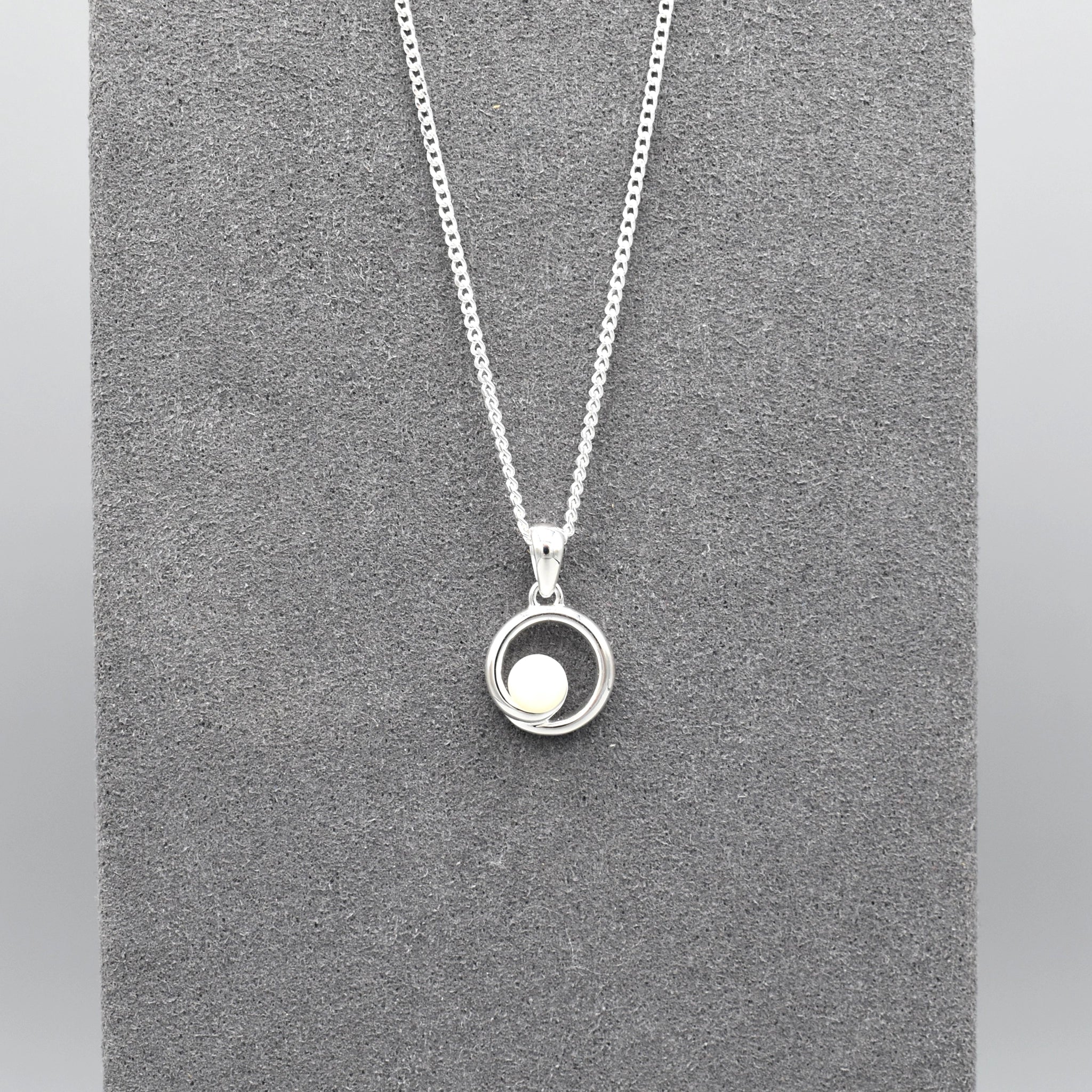 A round swirl pendant with a white pearl