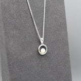 A round swirl pendant with a white pearl