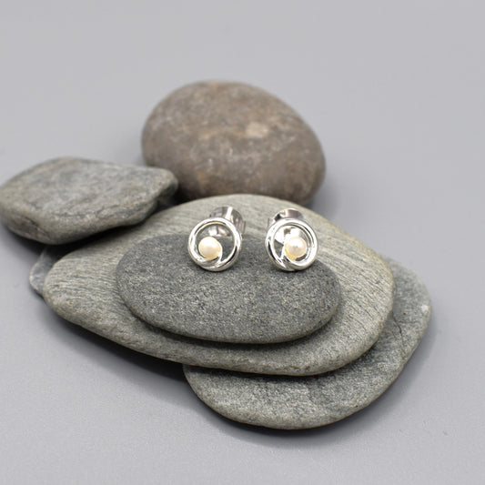 A pair of round swirl stud earrings with a freshwater pearl