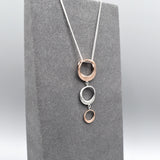 Pendant with three graduated irregular shaped circle drops in rose gold and silver side view