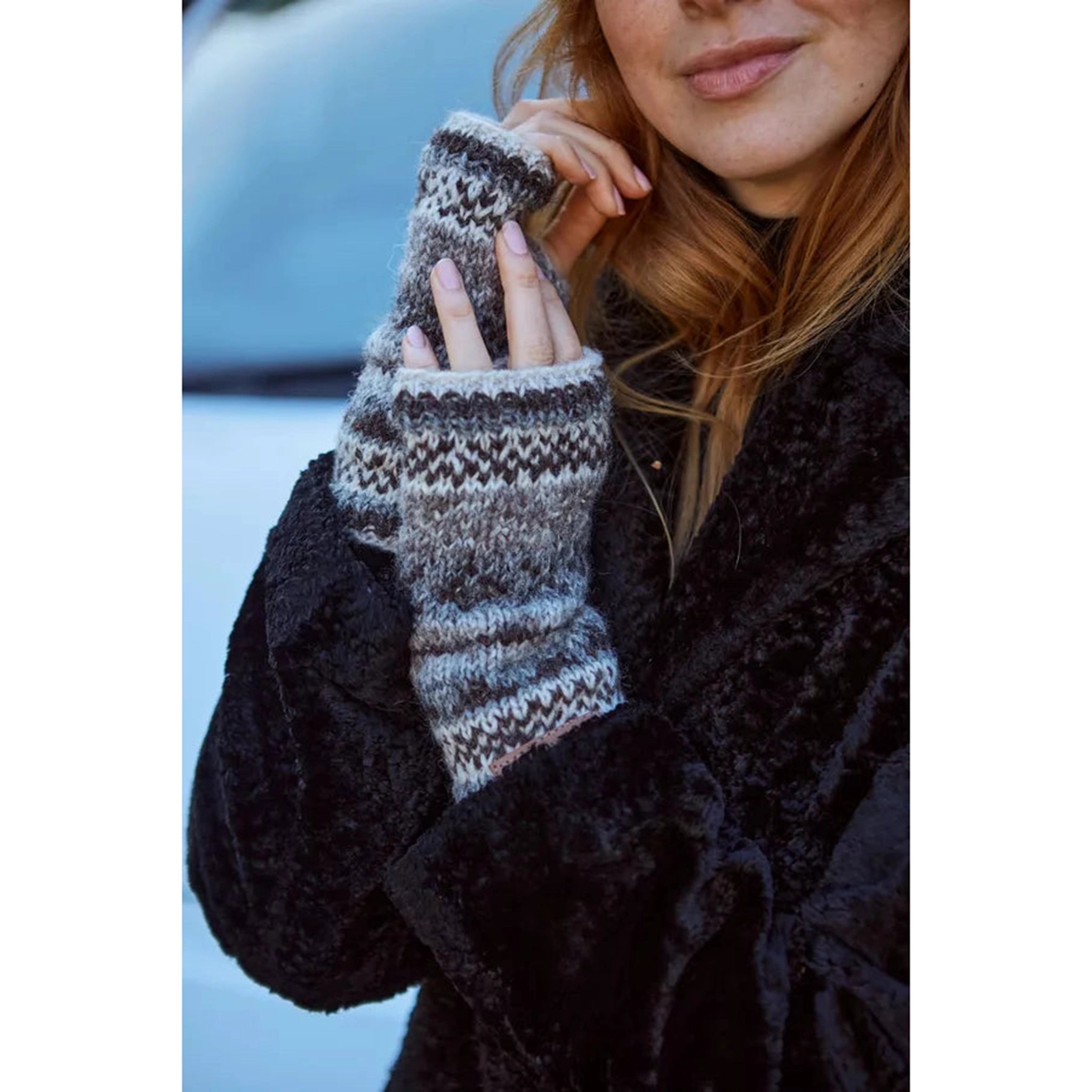 A pair of fairisle patterned thick knitted hand warmers in natural colours
