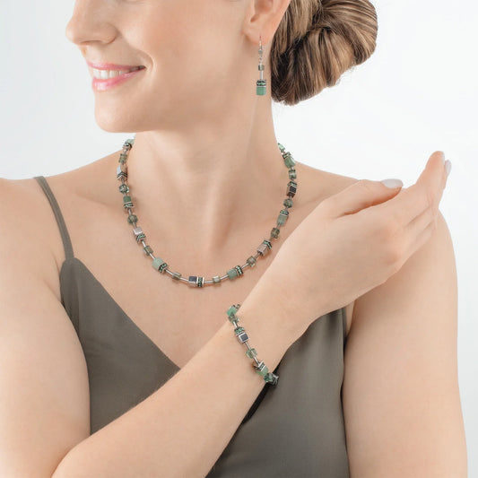 Model wearing a steel jewellery set featuring a variety of cube shaped stones including green aventurine