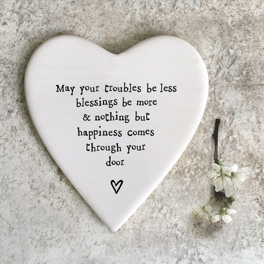 A white ceramic heart shaped coaster featuring a quote and a heart