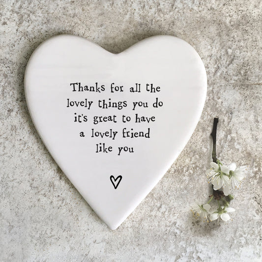 A white ceramic heart shaped coaster featuring a quote and a heart