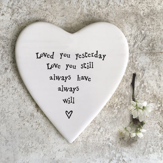 A white ceramic heart shaped coaster featuring a quote and a heart 