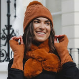 Model wearing nutmeg brown pompom coloured hat, fingerless gloves, and faux fur scarf