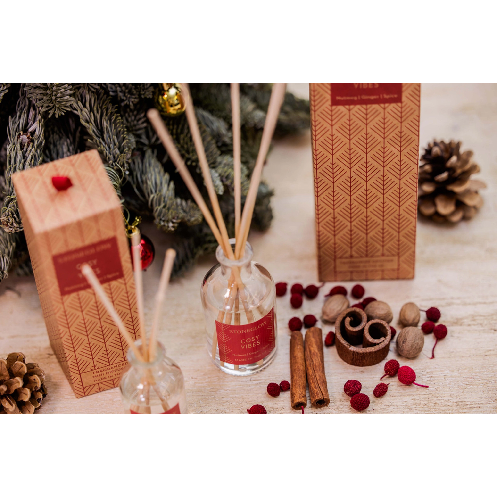 A glass reed diffuser with a box decorated with Scandi style red trees - lifestyle image