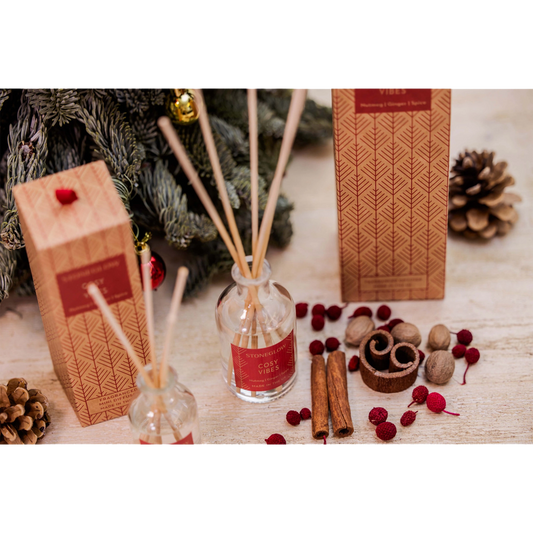 A glass reed diffuser with a box decorated with Scandi style red trees - lifestyle image