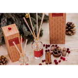 A glass reed diffuser with a box decorated with Scandi style red trees - lifestyle image