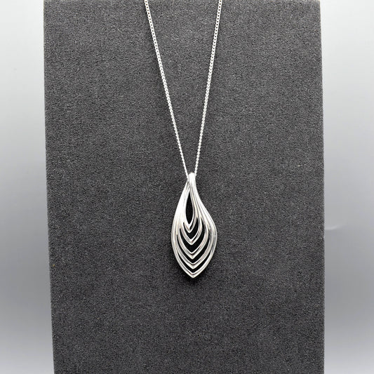 A simple modern silver pendant with a layered marquis shape on a silver chain.