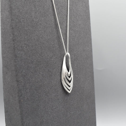 A simple modern silver pendant with a layered marquis shape on a silver chain.