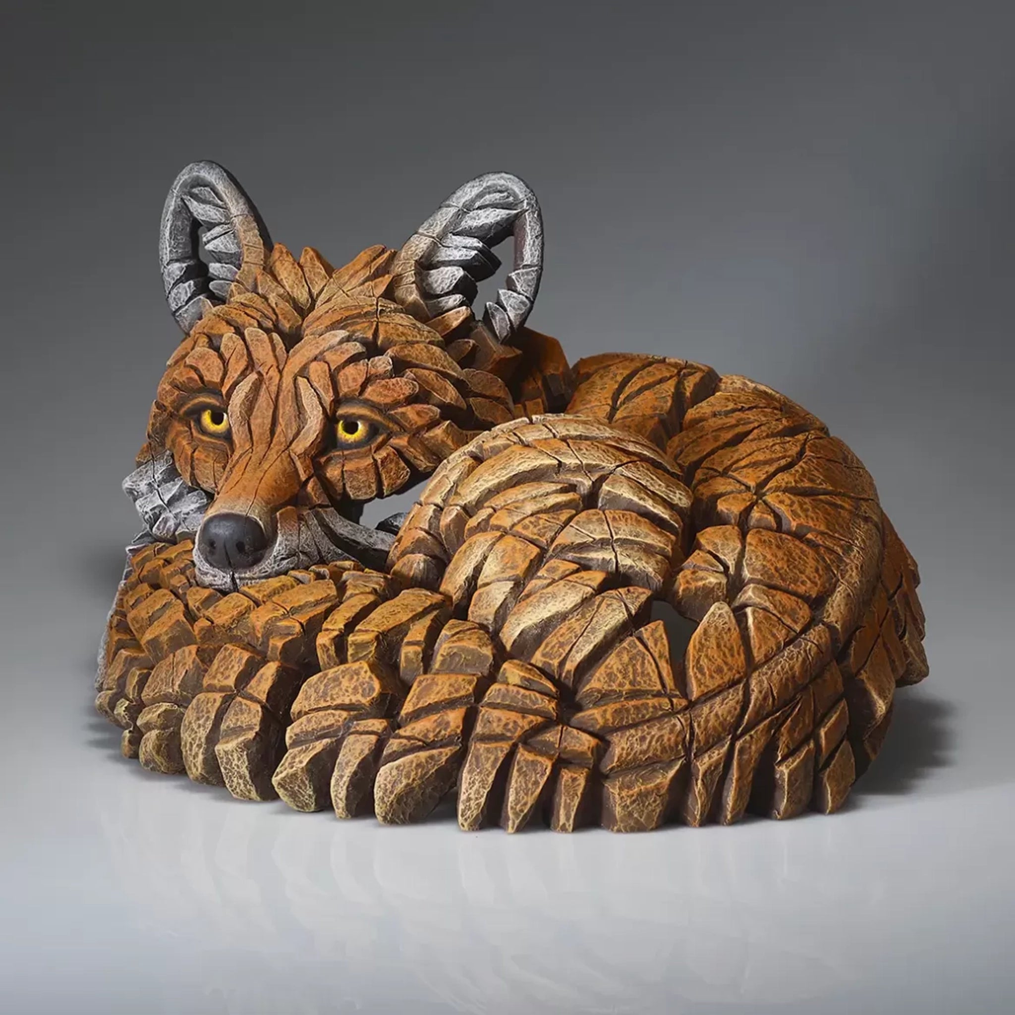 A painted sculpture of a curled up red fox