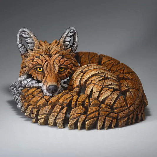 A painted sculpture of a curled up red fox