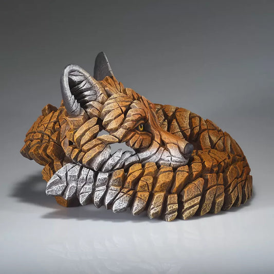 A sculpture of a curled up red fox side view