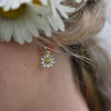 Model wearing polished silver daisy drop earrings with yellow and white enamel on silver stud posts