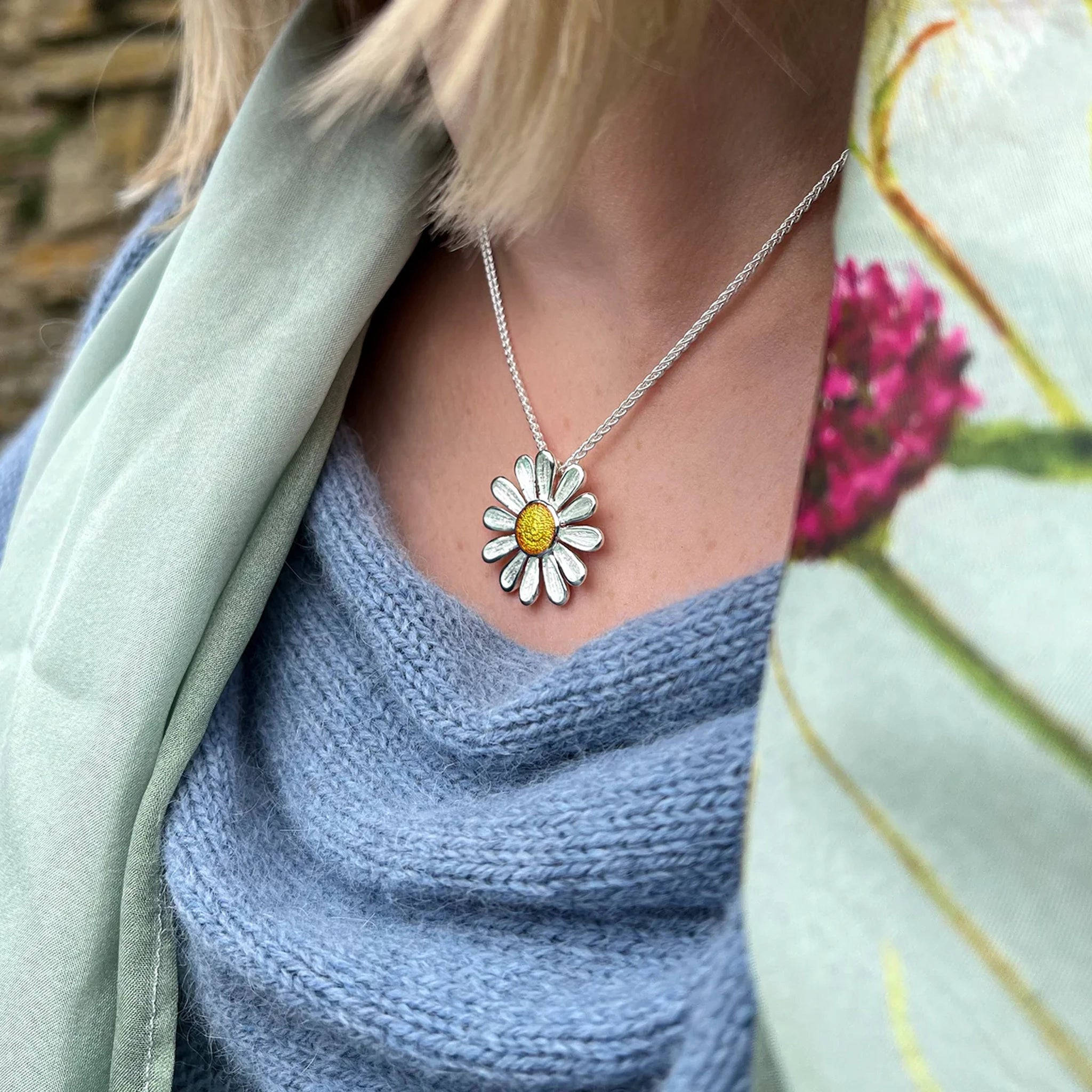 Model wearing a polished silver large daisy pendant in yellow and white enamel with a silver chain