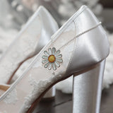 A pair of wedding shoes with a  polished silver large daisy pendant in yellow and white enamel with a silver chain