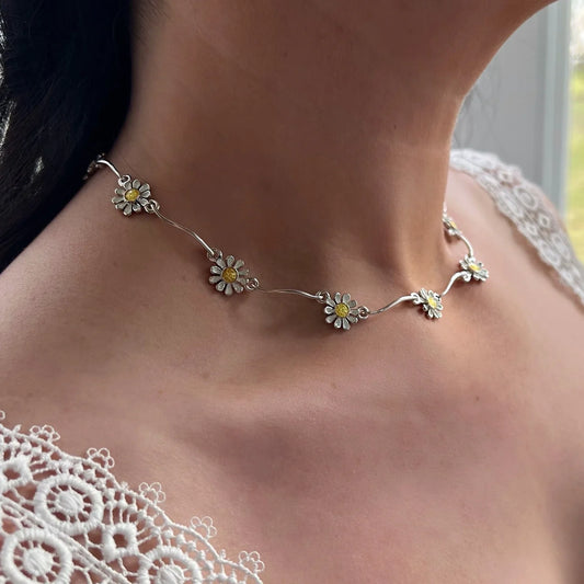 Model wearing a polished silver daisy necklace with repeating links in yellow and white enamel