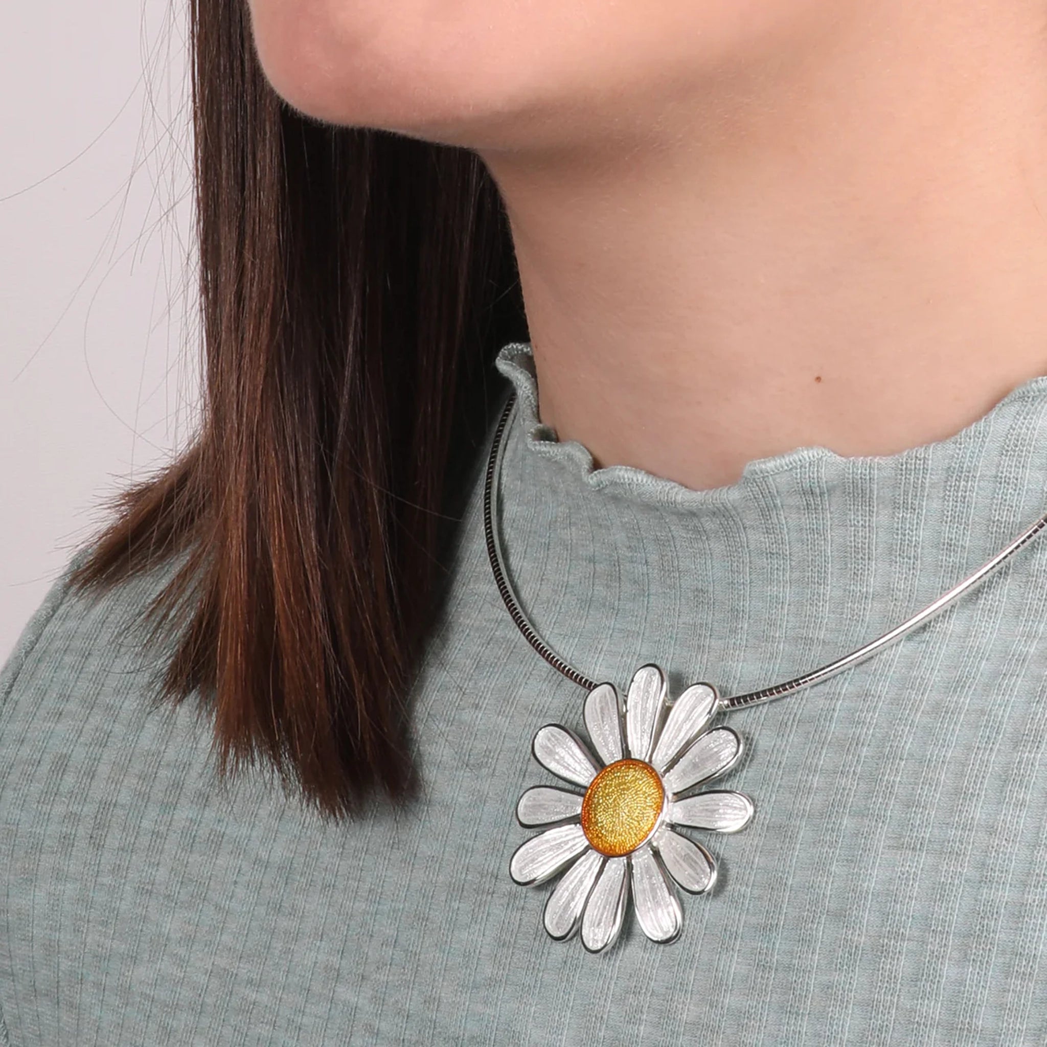 Model wearing polished silver daisy necklet in white and yellow enamel on a silver neck wire