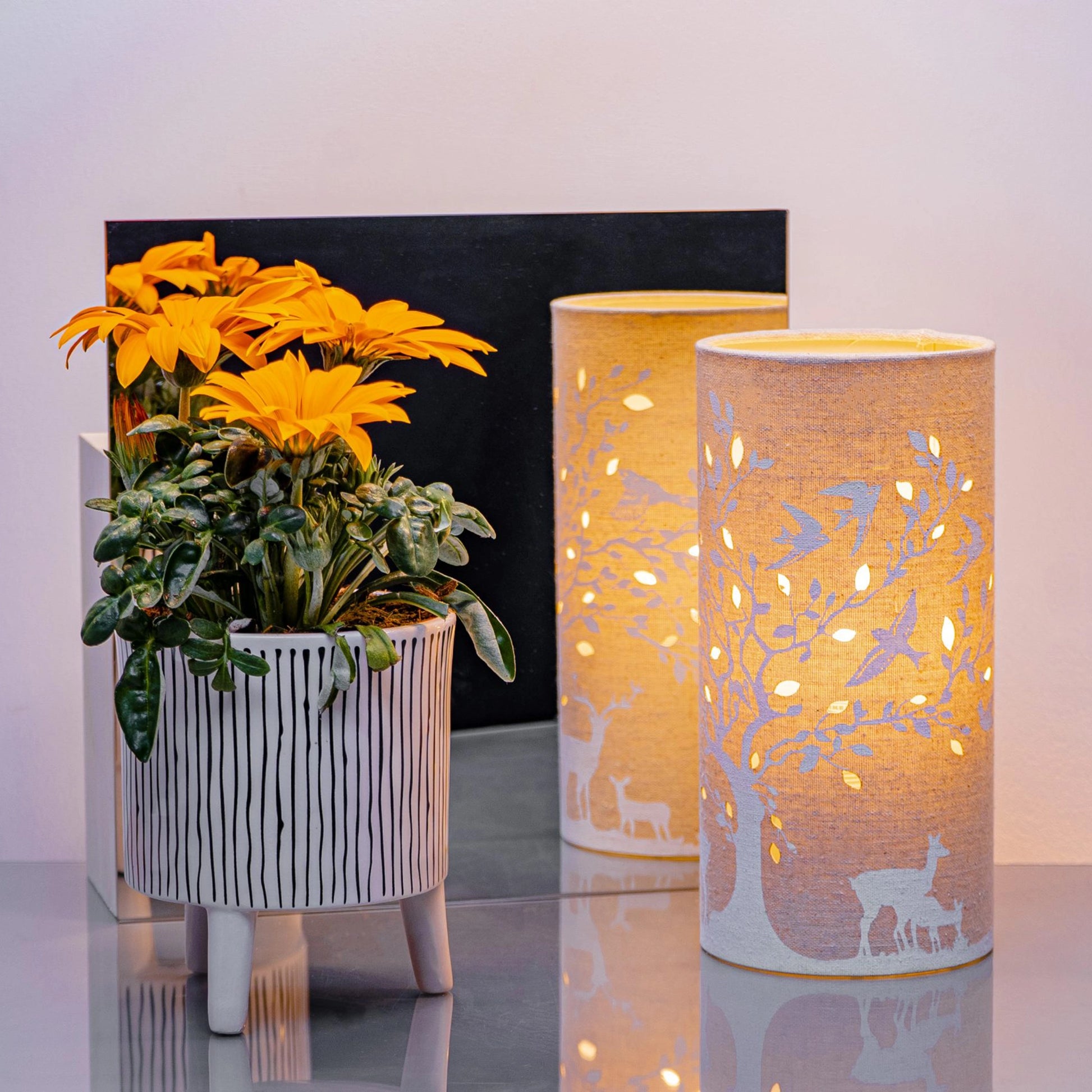 A linen look fabric table lamp with a tree and deer design and cut out leaf details lifestyle