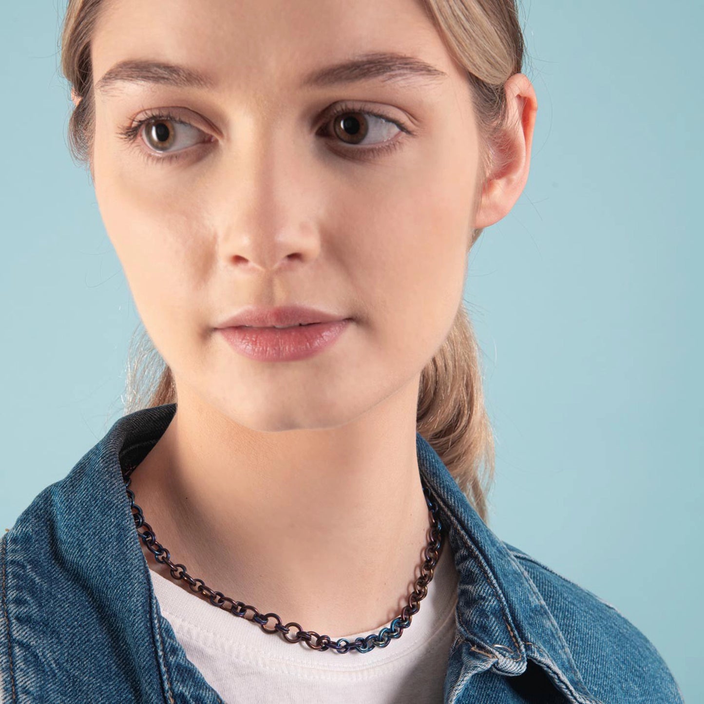 Model wearing a chain linked titanium necklace in denim blue and copper