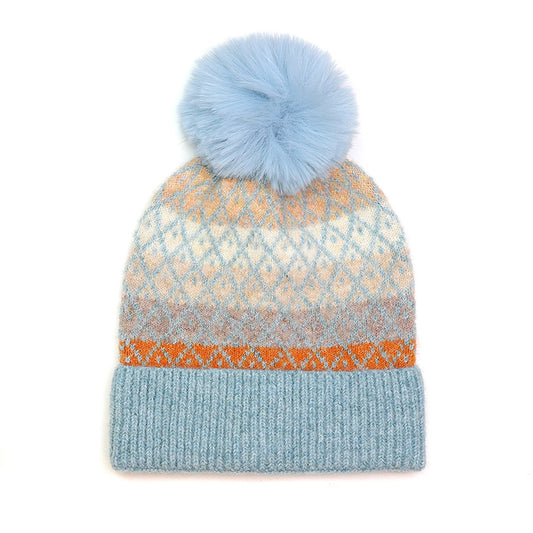 A striped hat in orange, natural tones and blue with a diamond pattern overlay and a fluffy blue pom pom