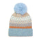 A striped hat in orange, natural tones and blue with a diamond pattern overlay and a fluffy blue pom pom