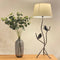 A curved forged steel table lamp with two bird details