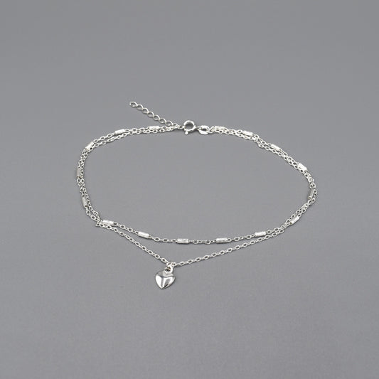 A double chain anklet with cylinder details and heart pendant