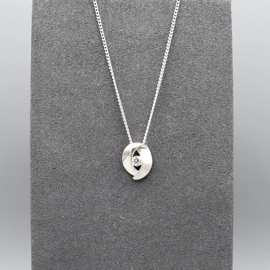 A double curve shaped silver pendant with CZ centre and matt texture