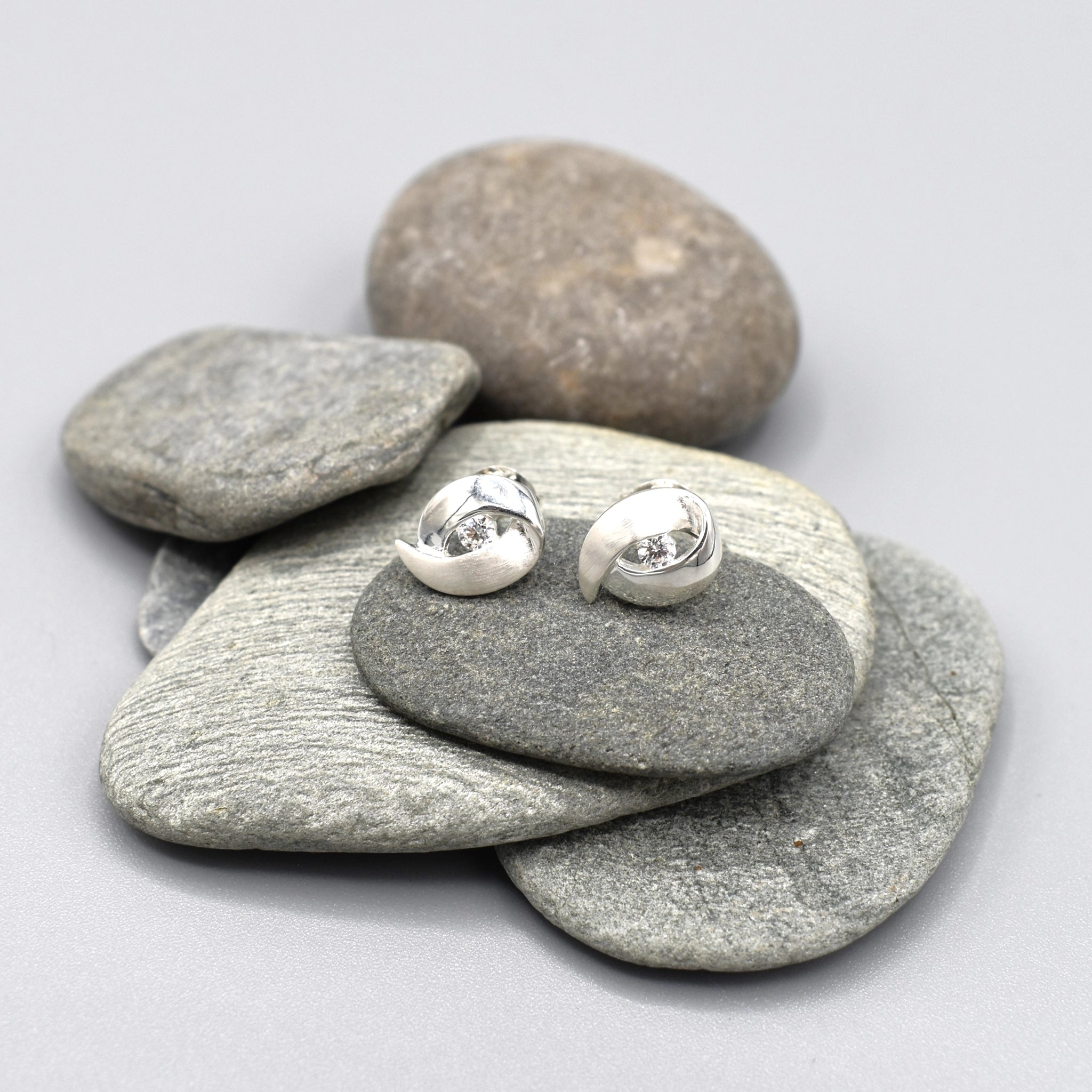 A pair of double curve shaped silver studs with CZ centre and matt texture