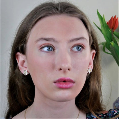 Model wearing satin finish silver stud earrings shaped like daisy flowers with gold centres