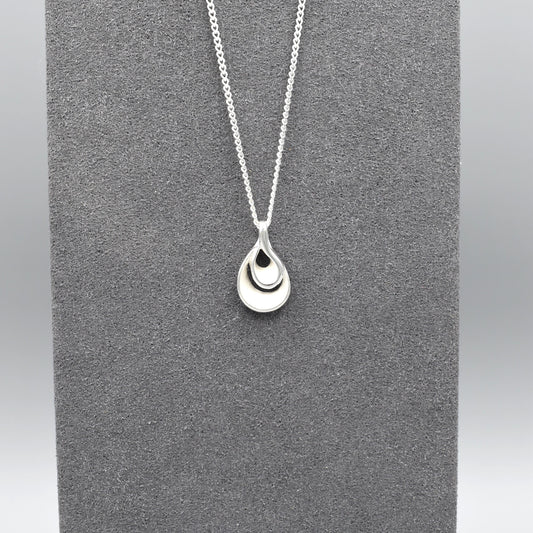 A double twisted teardrop shaped pendant with matt silver