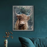 Framed canvas print of a red Highland cow with an impressionist blue background of foliage hanging in a dark room.