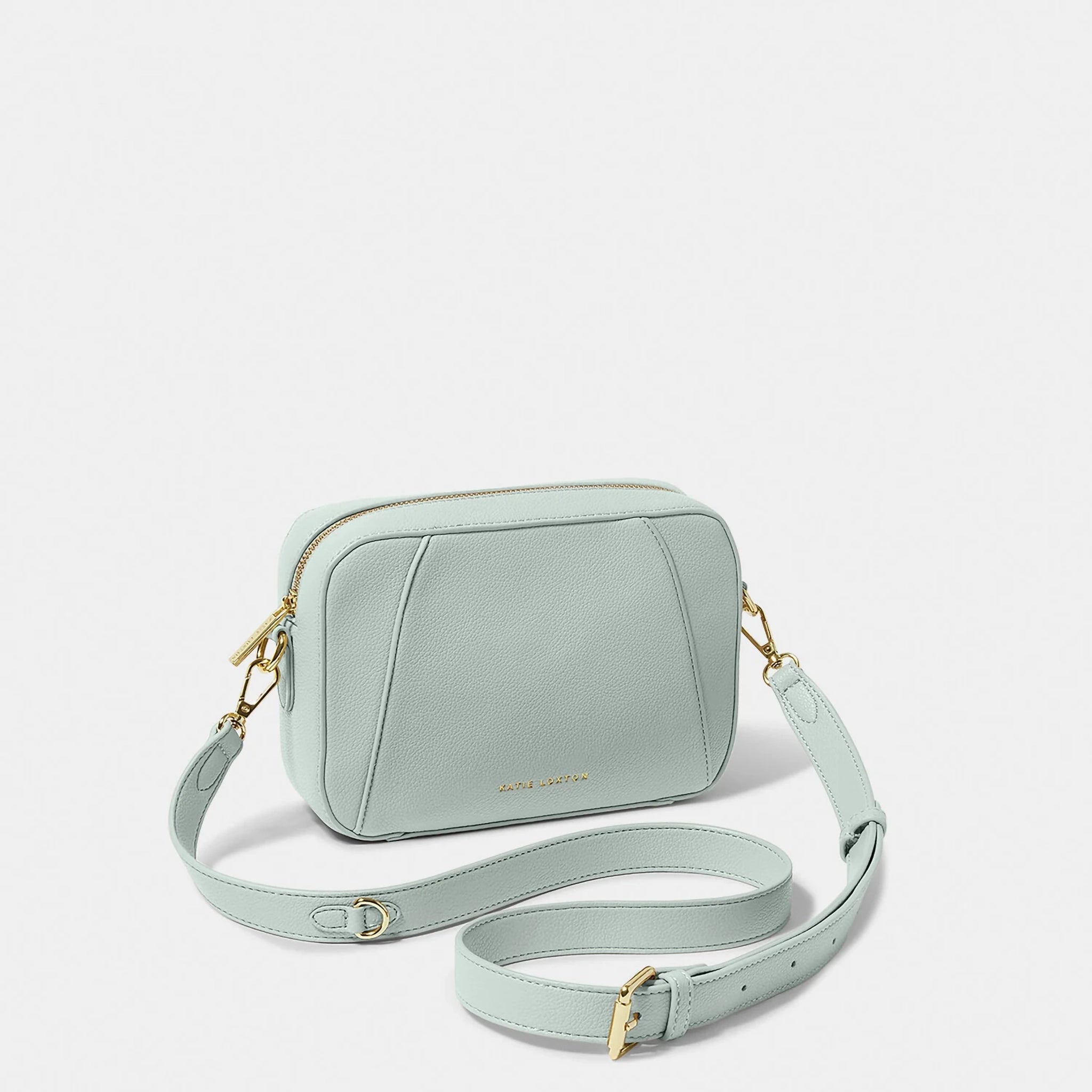 A light blue crossbody bag in a simple box shape with adjustable strap and gold hardware
