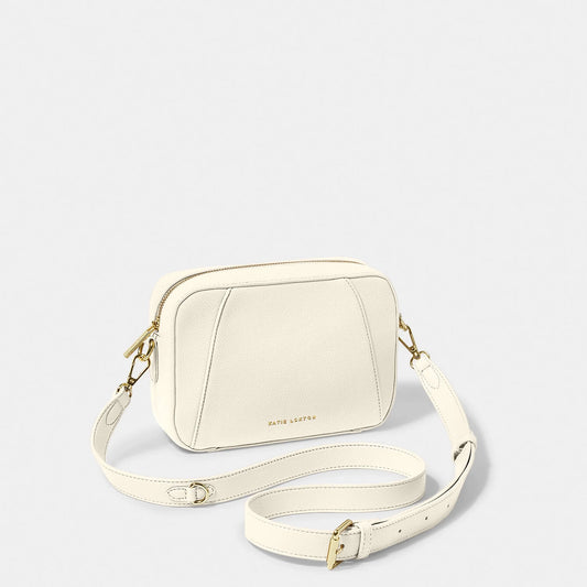 A ecru crossbody bag in a simple box shape with adjustable strap and gold hardware