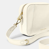 Detail of ecru crossbody bag in a simple box shape with adjustable strap and gold hardware